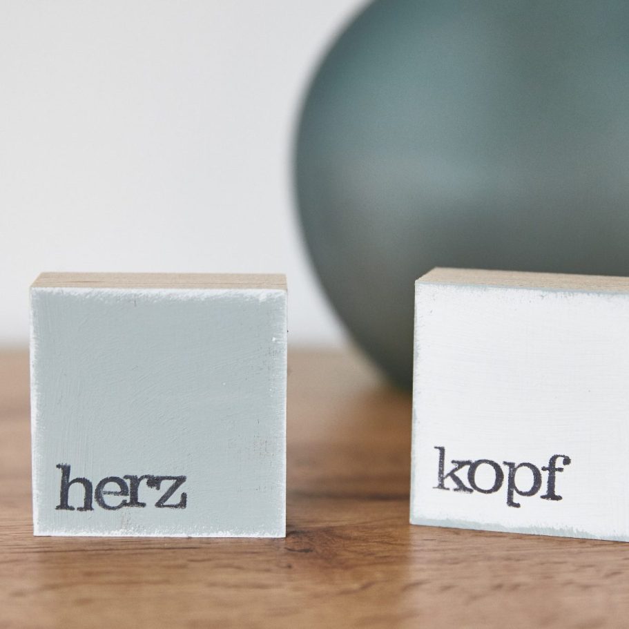 Holzobjekte mit den Aufschriften „Herz“ und „Kopf“ als Symbol für Balance